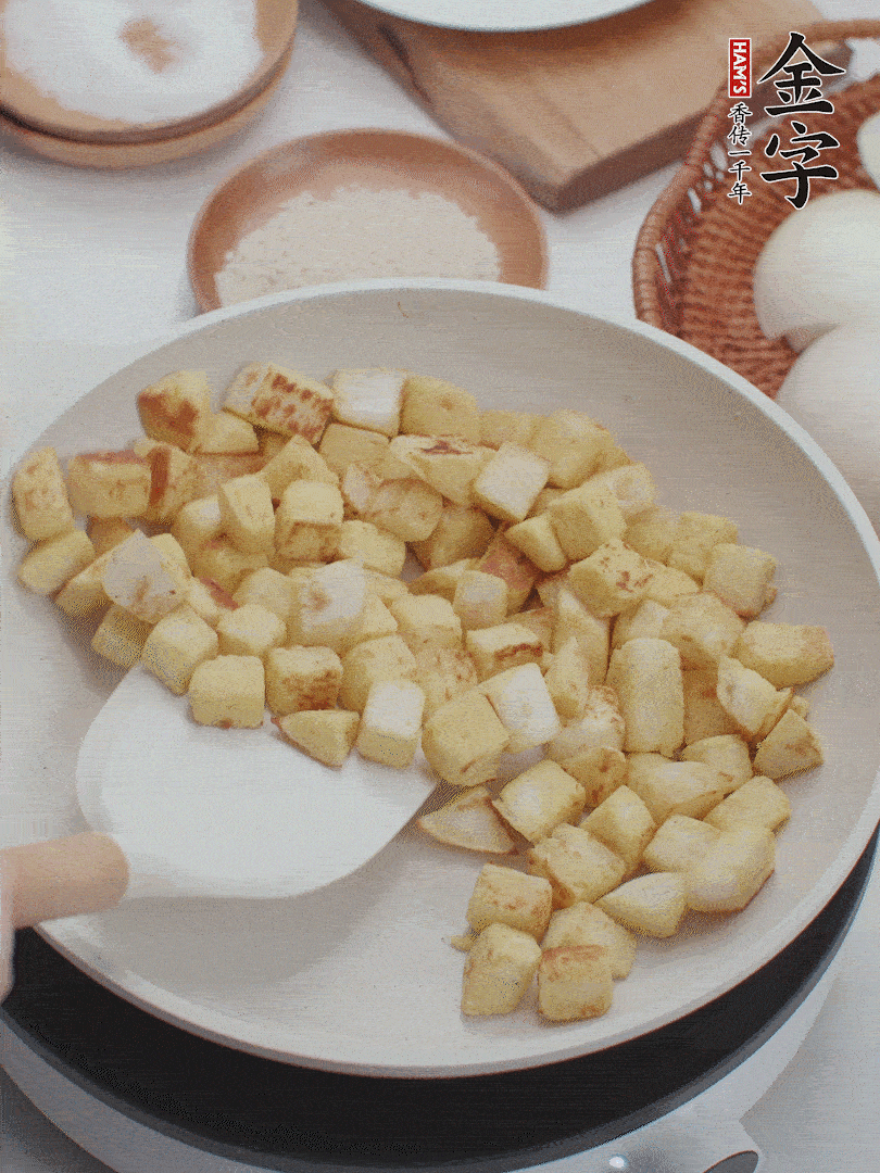 起鍋熱油，倒入饅頭丁，小火煎至蛋液凝固定型再翻面，饅頭丁部煎至金黃時(shí)盛起待用。